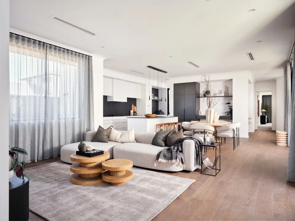 Modern open-plan living room with sleek kitchen, cozy sofa, wooden accents, and elegant dining area.