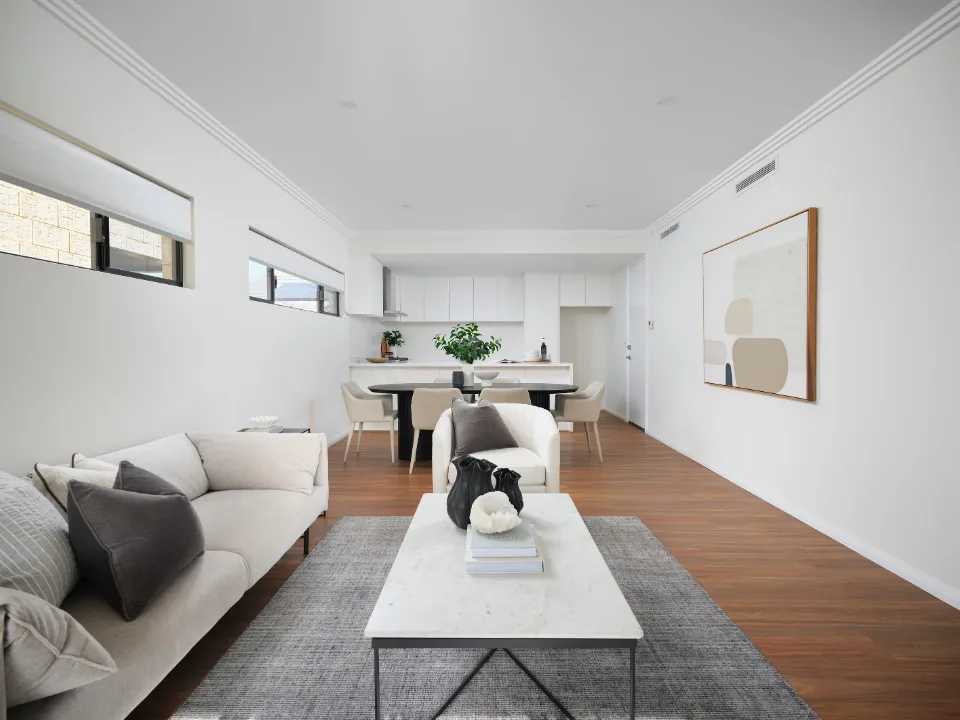 Modern open-plan living room with neutral decor and hardwood floors.