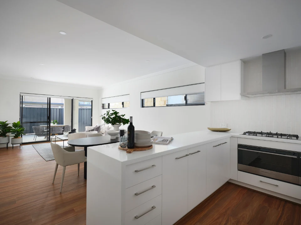 Modern open-plan kitchen and living area with sleek white cabinetry and wooden floors.