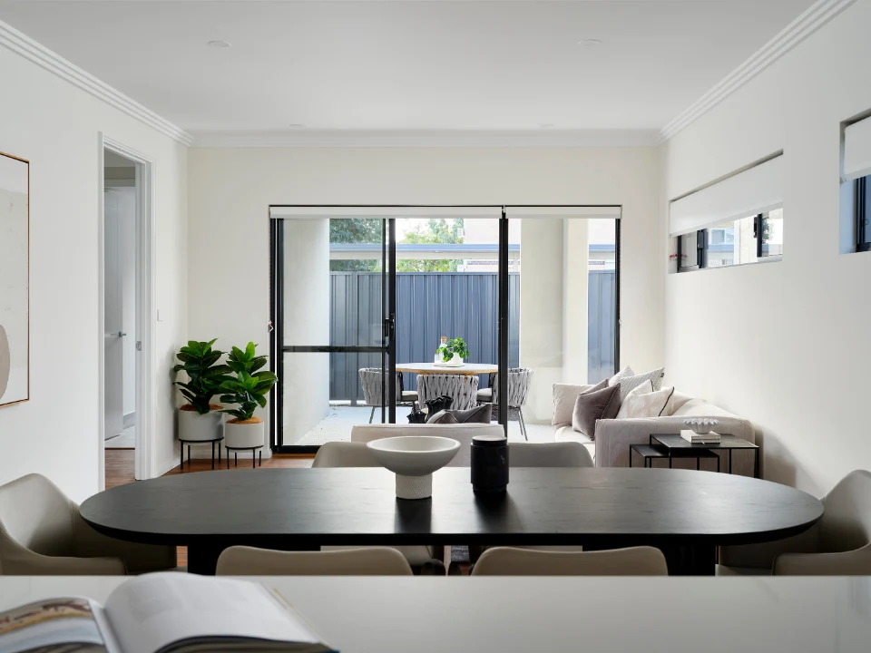 Modern open-plan living room with dining area, glass doors, and garden view. Cozy and stylish interior design.
