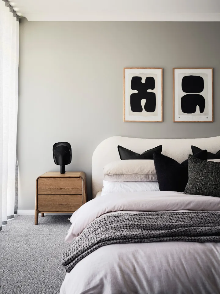 Modern bedroom with cozy bed, gray accents, and abstract wall art.