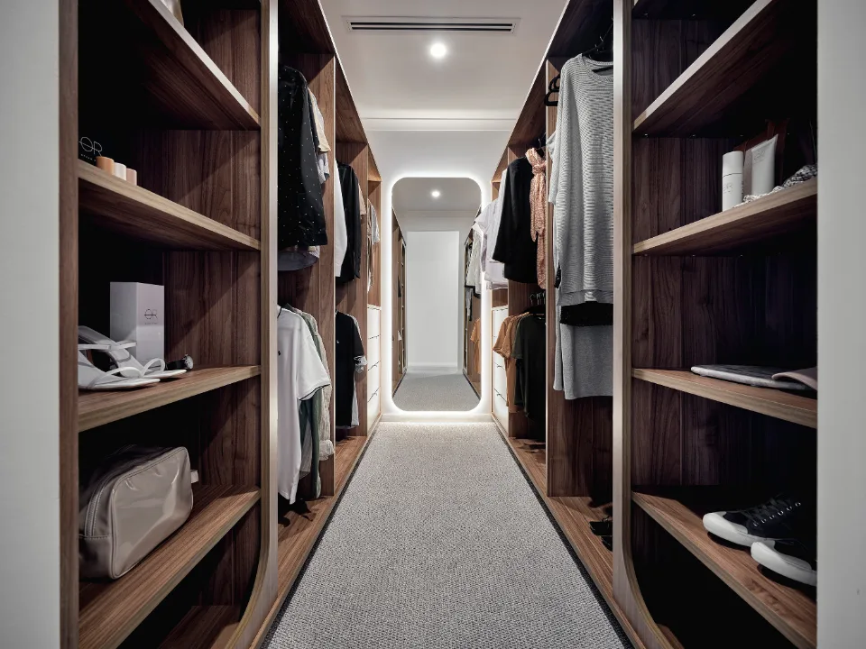 Luxurious modern walk-in wardrobe with wooden shelves and stylish clothing arrangement.