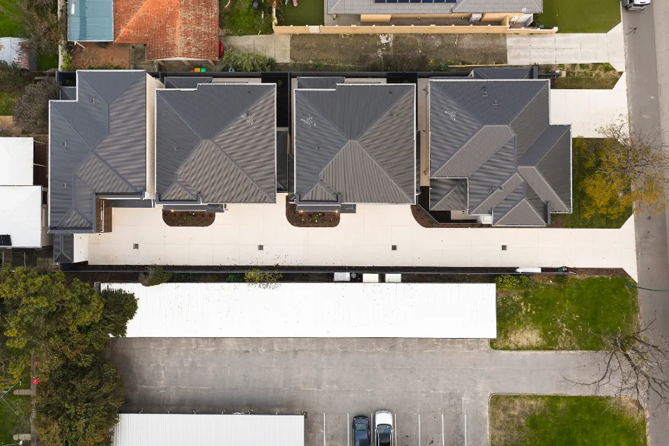 Aerial view of residential neighborhood with modern houses featuring dark roofs and shared driveways.