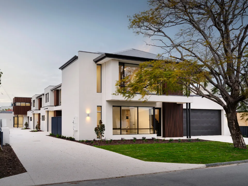 Modern two-story house with garage and garden, featuring large windows and sleek design.