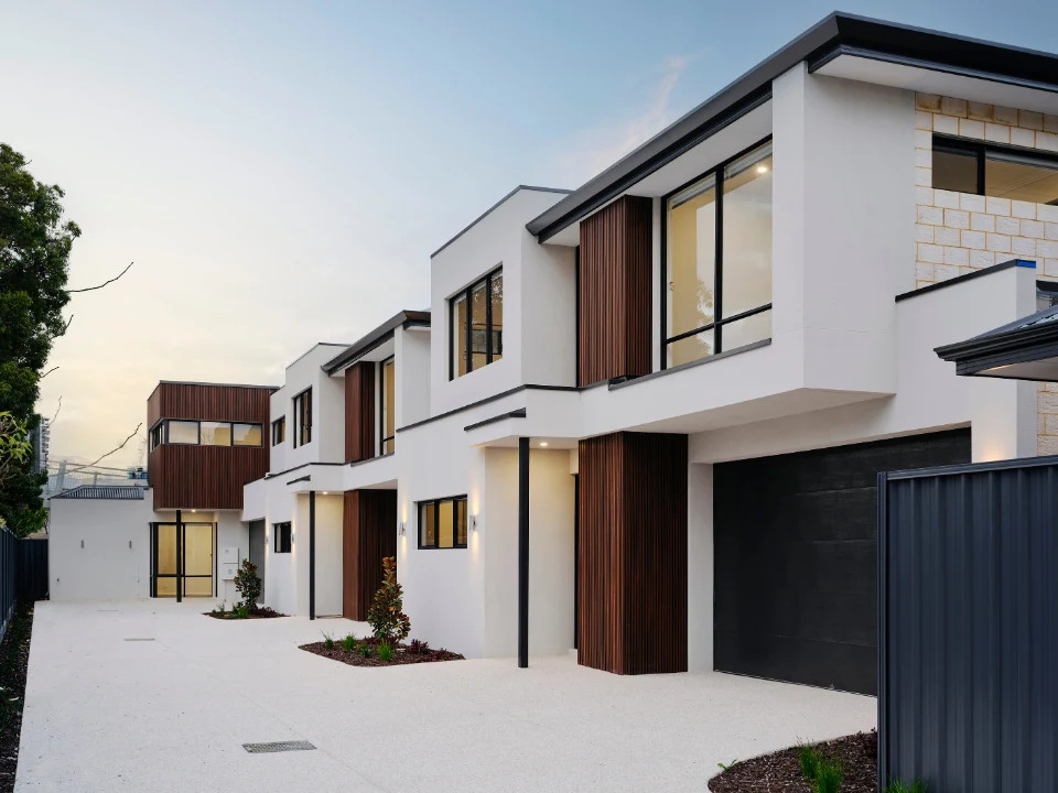 Modern two-story house with clean design, wood accents, and large windows at dusk.