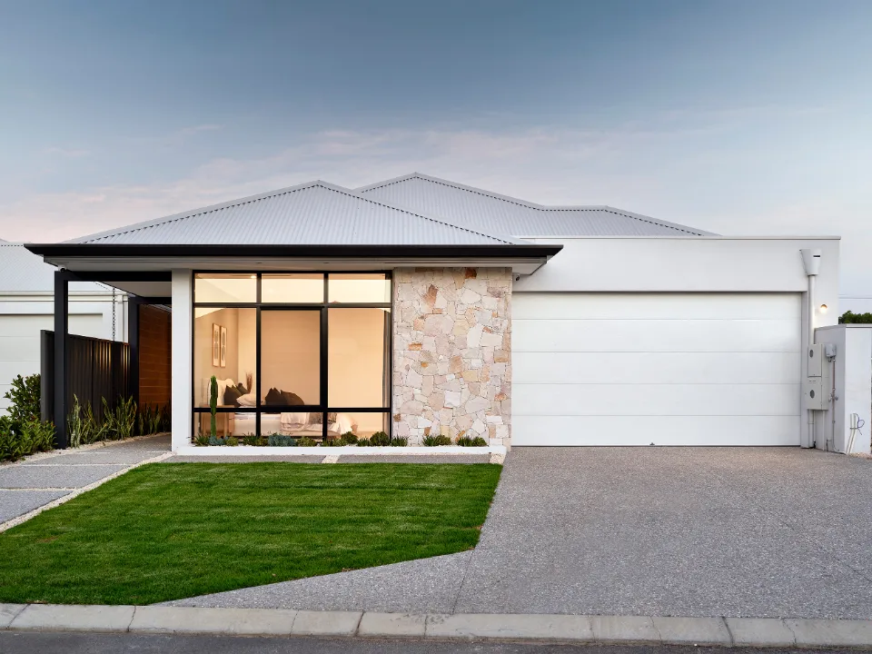 Modern suburban house with large windows and a stone exterior, featuring a green lawn and double garage.