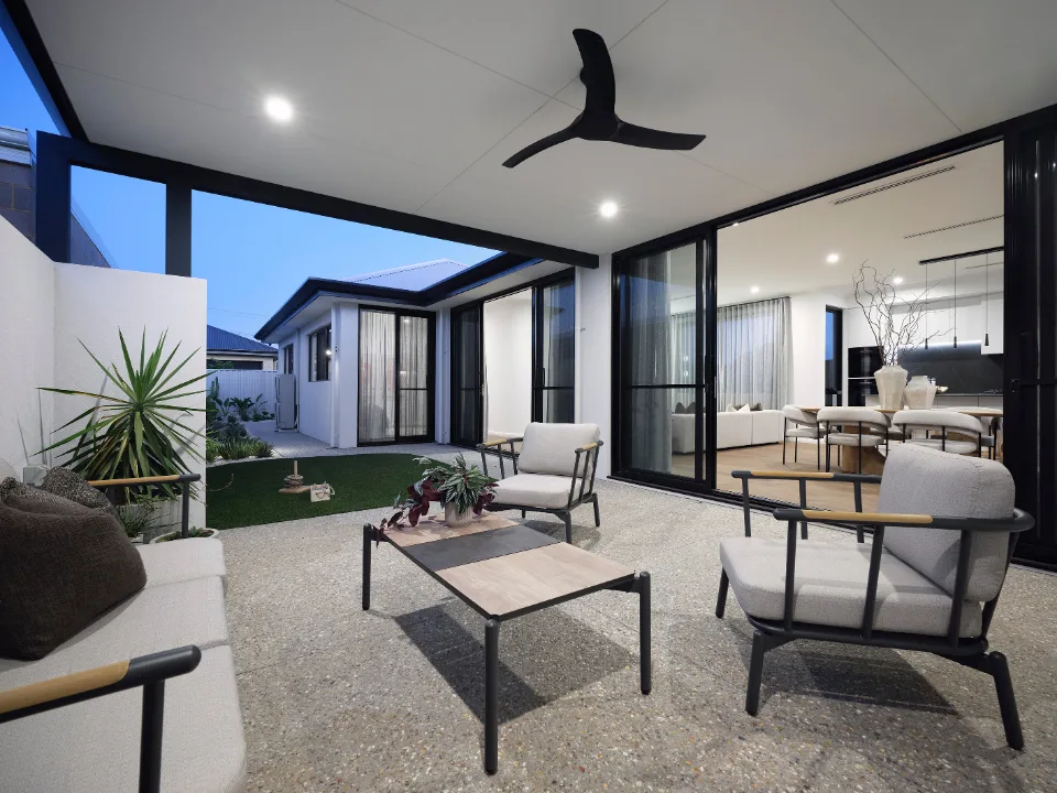 Modern outdoor patio with comfortable seating, stylish tables, and a ceiling fan, leading to open-plan living area.