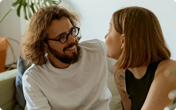Couple smiling and sitting together on a couch in a cozy living room setting.