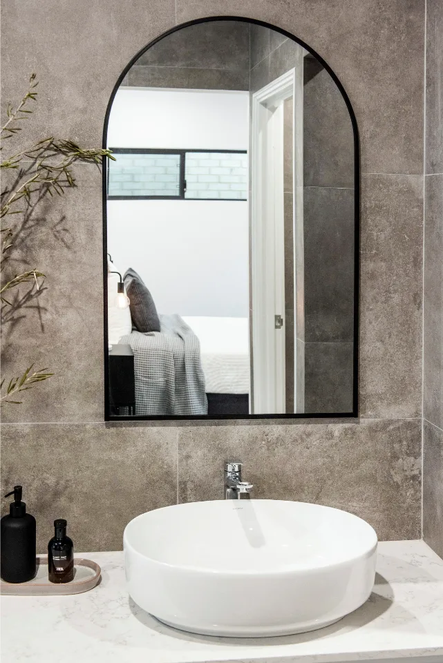 Modern bathroom with an oval mirror, sleek white sink, and minimalist decor for a stylish, contemporary look.