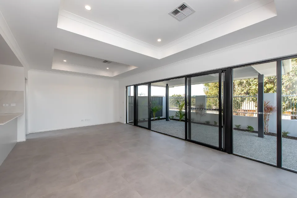 Modern empty living room with large glass windows and garden view.