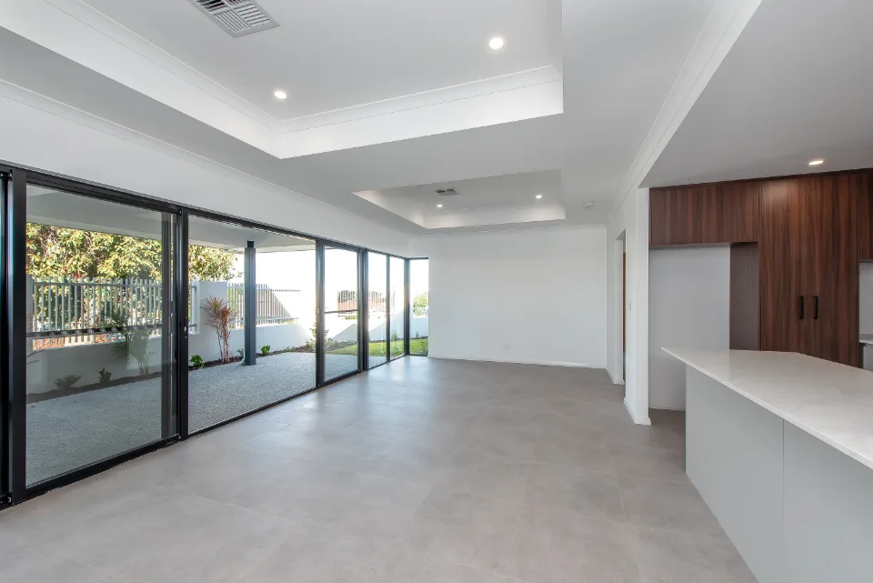 Open-plan living room with large windows and modern kitchen, featuring a sleek design and natural lighting.