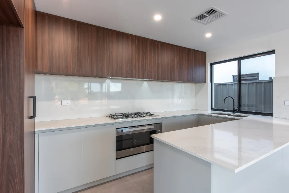 Modern kitchen with wood cabinets, marble countertops, and built-in appliances.