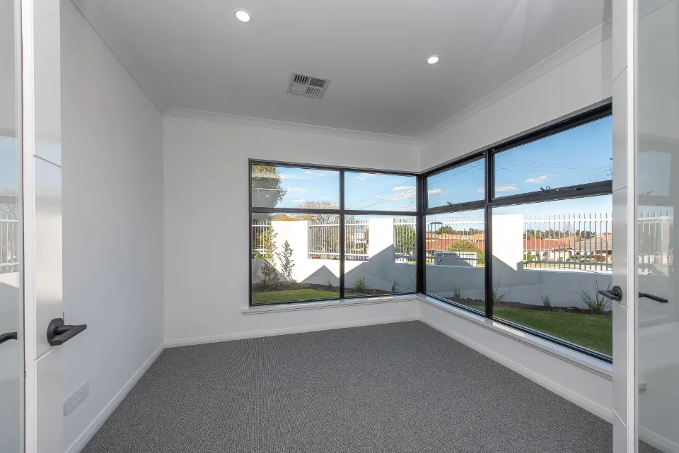 Bright empty room with large corner windows and garden view.