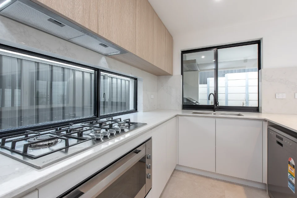 Modern kitchen with sleek cabinetry, gas stove, and large windows for natural light.