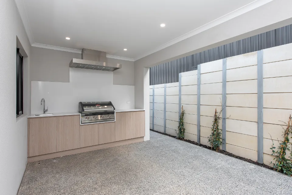 Modern outdoor kitchen with grill, countertop, and sink in a spacious patio area.