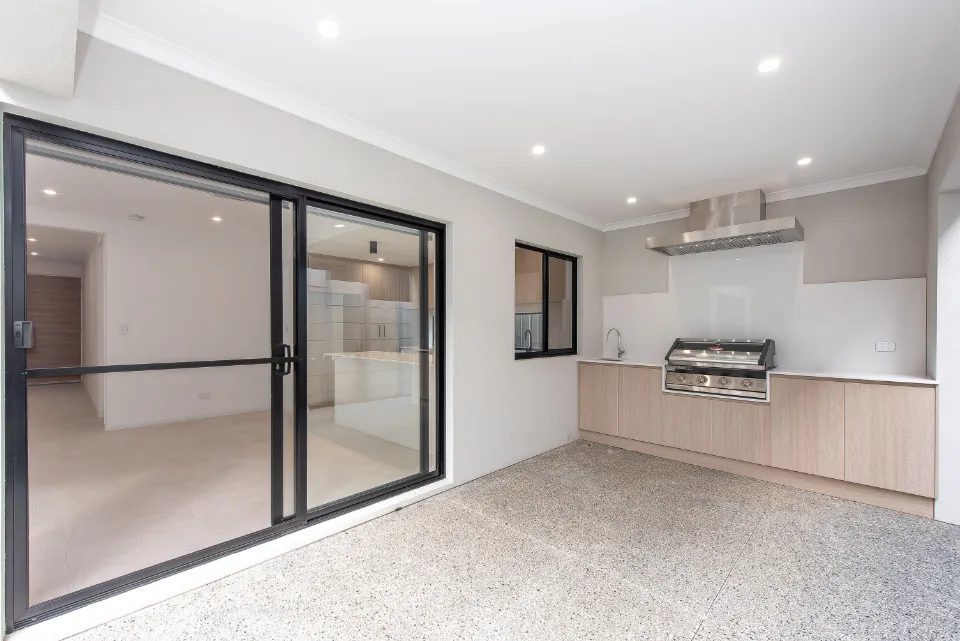 Modern indoor kitchen with built-in grill, sliding glass door, and sleek cabinetry.