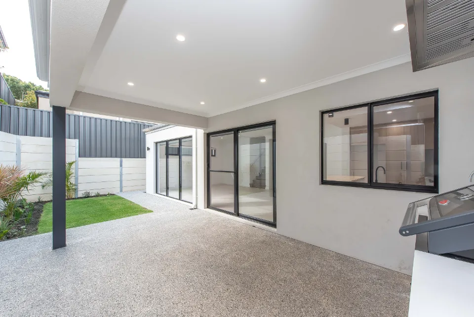 Modern covered patio area with sliding glass doors and outdoor lighting.