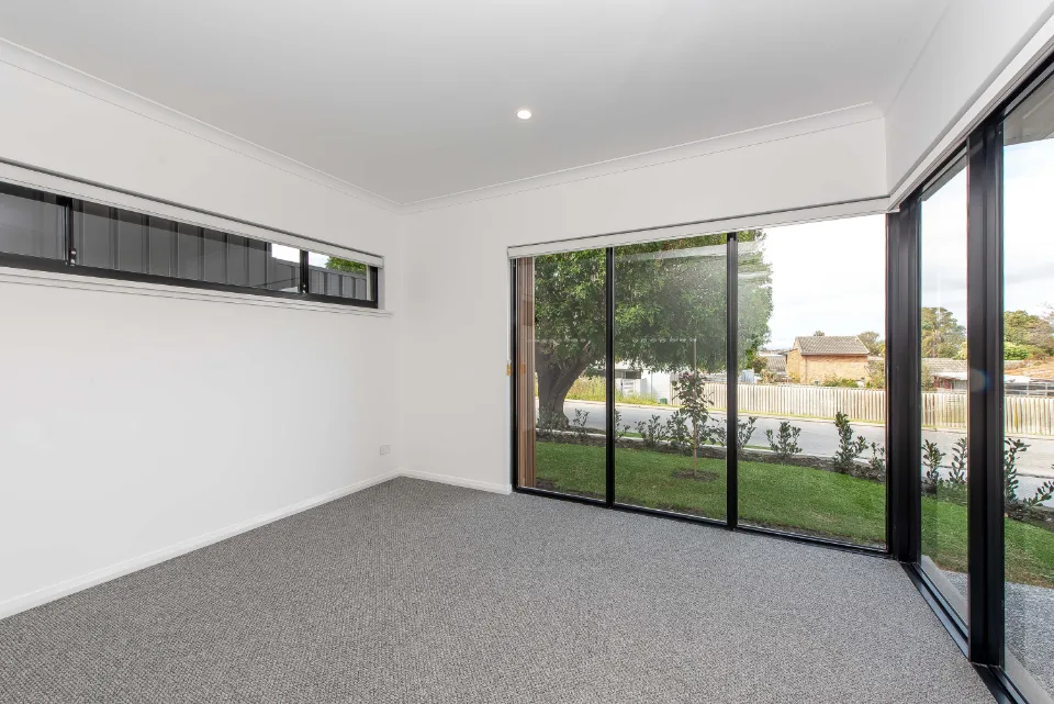 Bright empty room with large windows overlooking a green garden, modern home interior design.