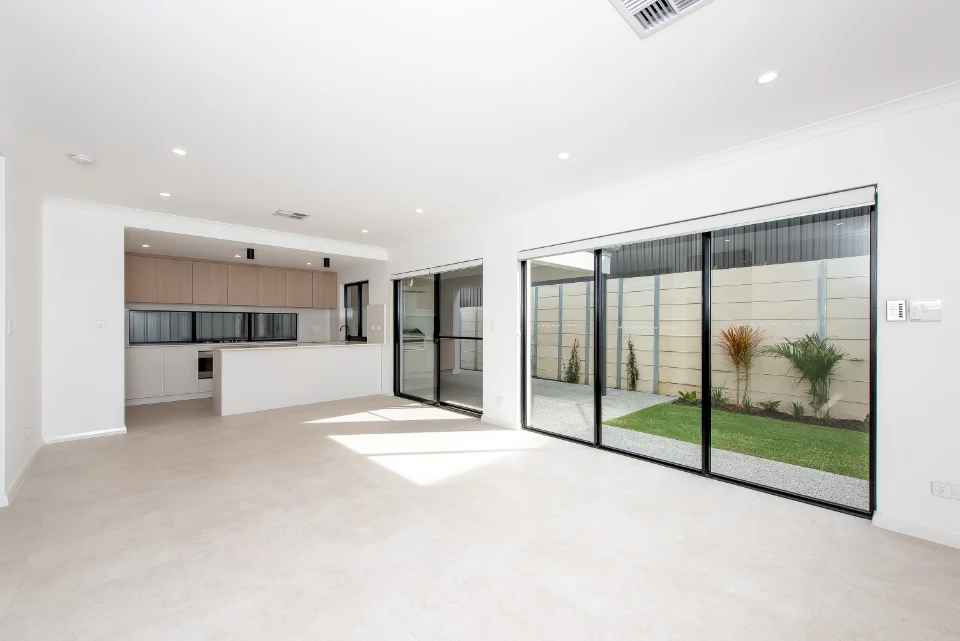 Modern open-plan kitchen and living area with large glass doors opening to a garden. Bright and spacious interior.