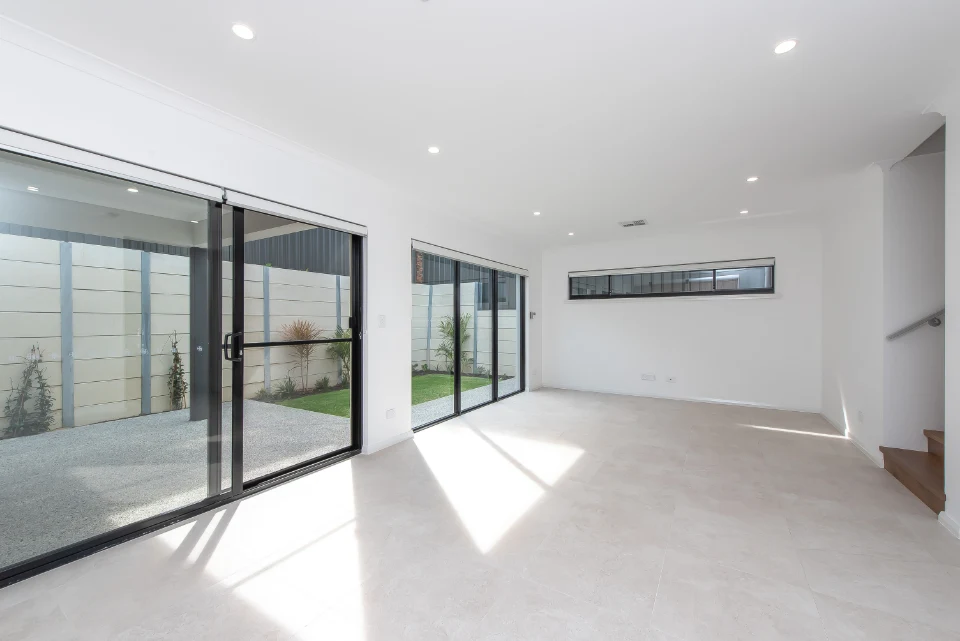 Bright modern living room with large sliding glass doors opening to a courtyard.