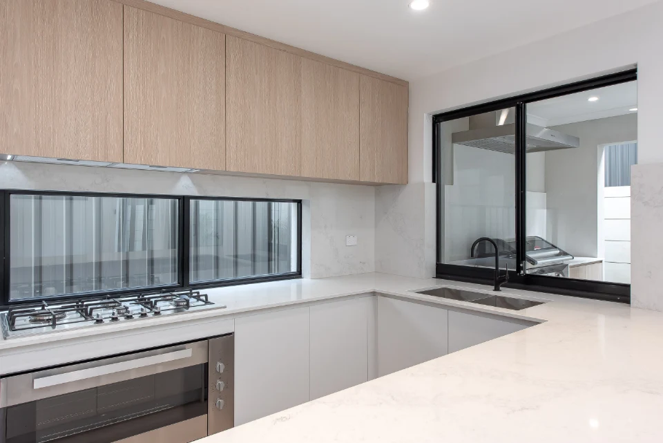 Sleek modern kitchen with marble countertops, gas stove, and large windows for natural light.