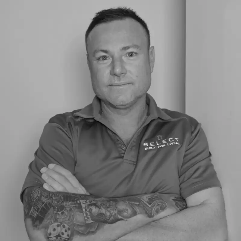 Andrew H, Site Manager. Professional black and white headshot, with tattoos, smiling in a branded polo shirt.
