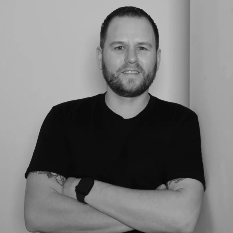 Andrew Wallace, Chief Financial Officer. A professional headshot with his arms crossed, wearing a black t-shirt.