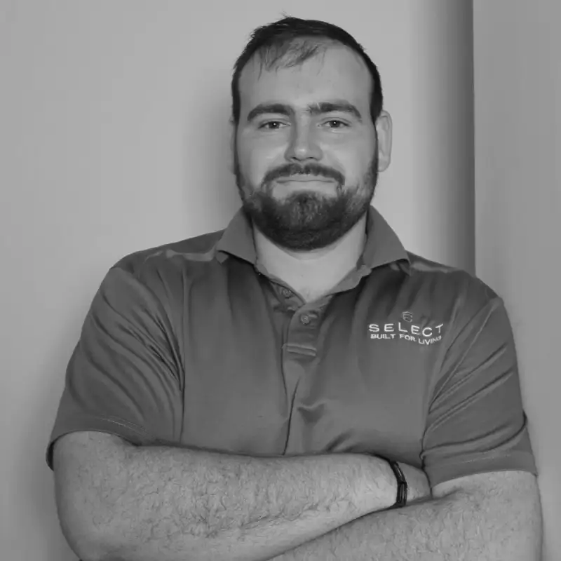 Caleb N, Site Manager. Professional black and white headshot, arms crossed, smiling in a branded polo shirt.