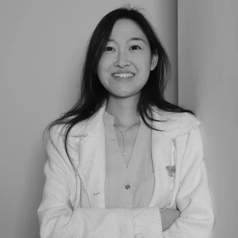 Daisy D, Wholesale Business Development Manager. Professional black and white headshot, smiling in a white jacket.