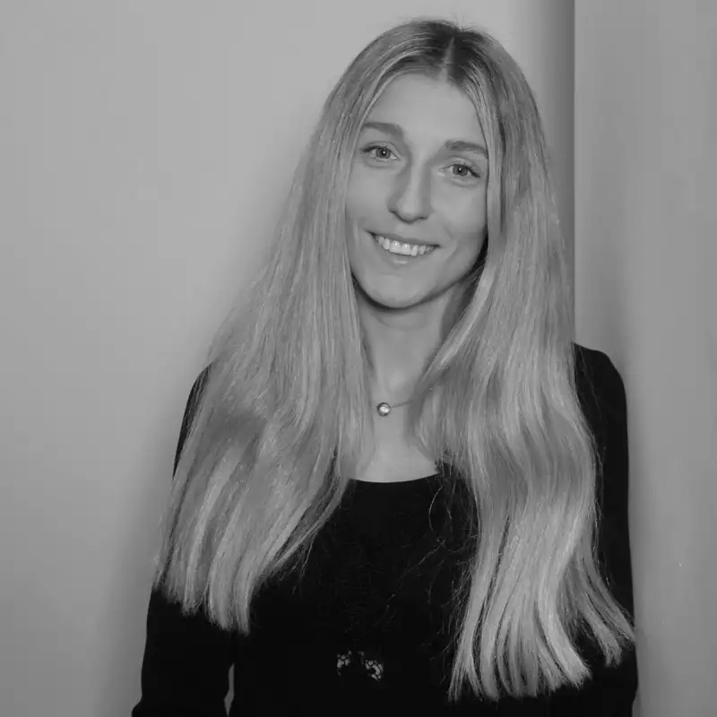 Janina G, Accounts Administrator. Professional black and white headshot, smiling with long blonde hair.