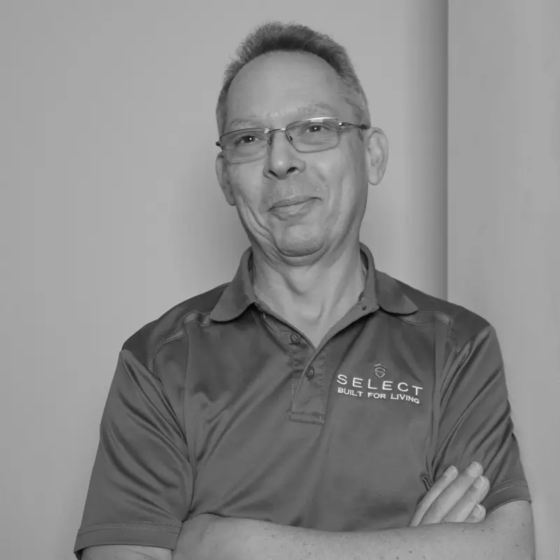 Juan B, Senior Scheduler. Professional black and white headshot, smiling with glasses in a branded polo shirt.
