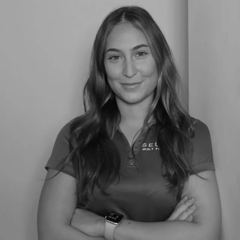 Lis A, Wholesale Admin. Professional black and white headshot, arms crossed, smiling in a branded polo shirt.