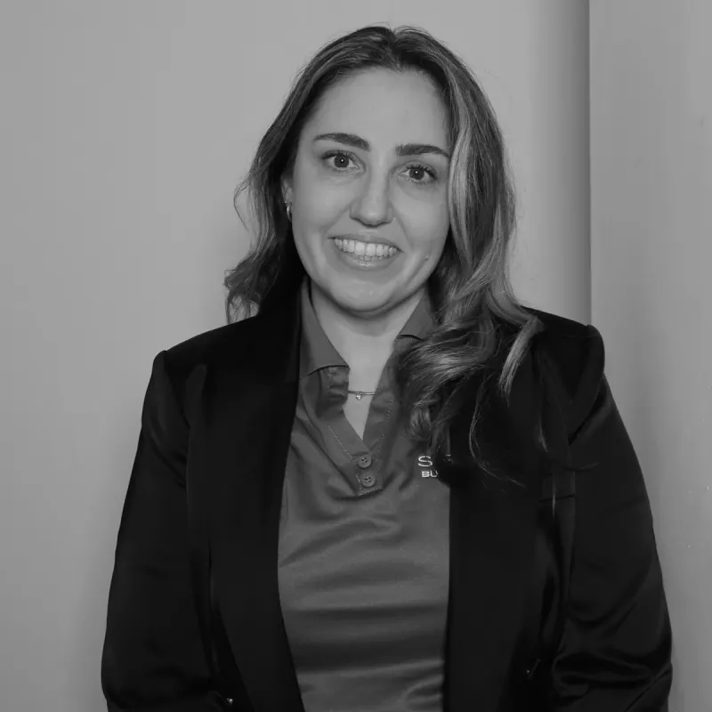 Mel S, Admin Team Leader. Professional black and white headshot, smiling in a black blazer and collared shirt.