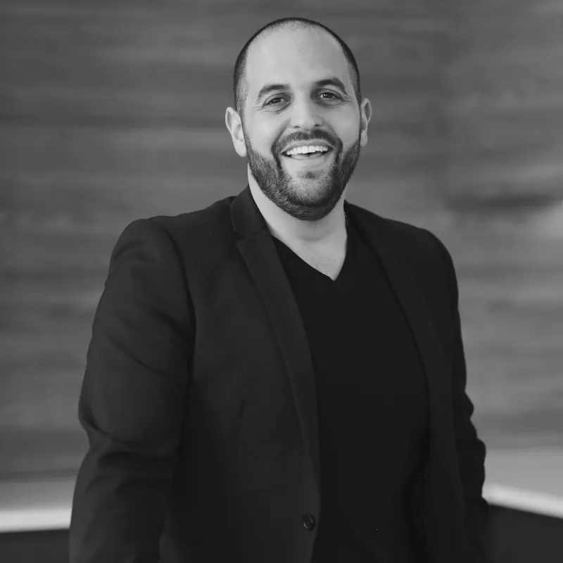 Michael Agostino, Director. A professional, smiling headshot of him in a dark blazer against a blurred background.